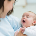 Mother holding a baby while he opens his mouth